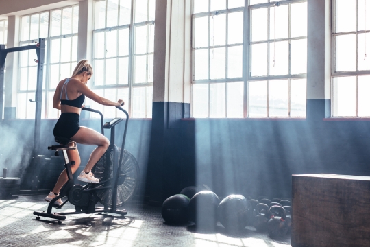 woman on exercise bike in gym training in the morning