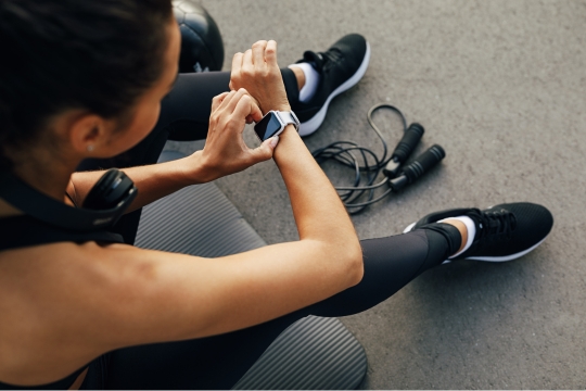 Female using smart watch sitting in gym