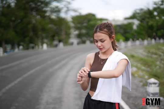 Female working out whilst looking at heart rate watch on roadside