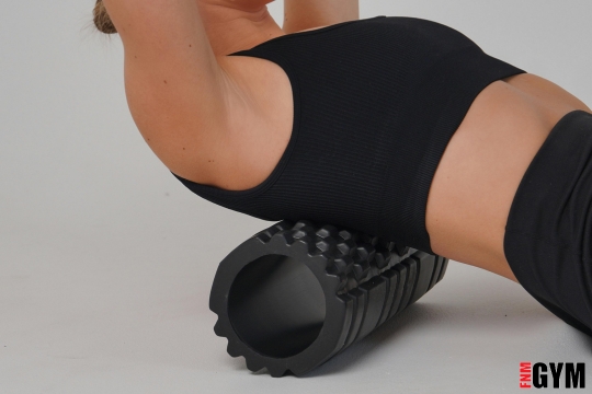 Female lying on spikey roller wearing black crop top