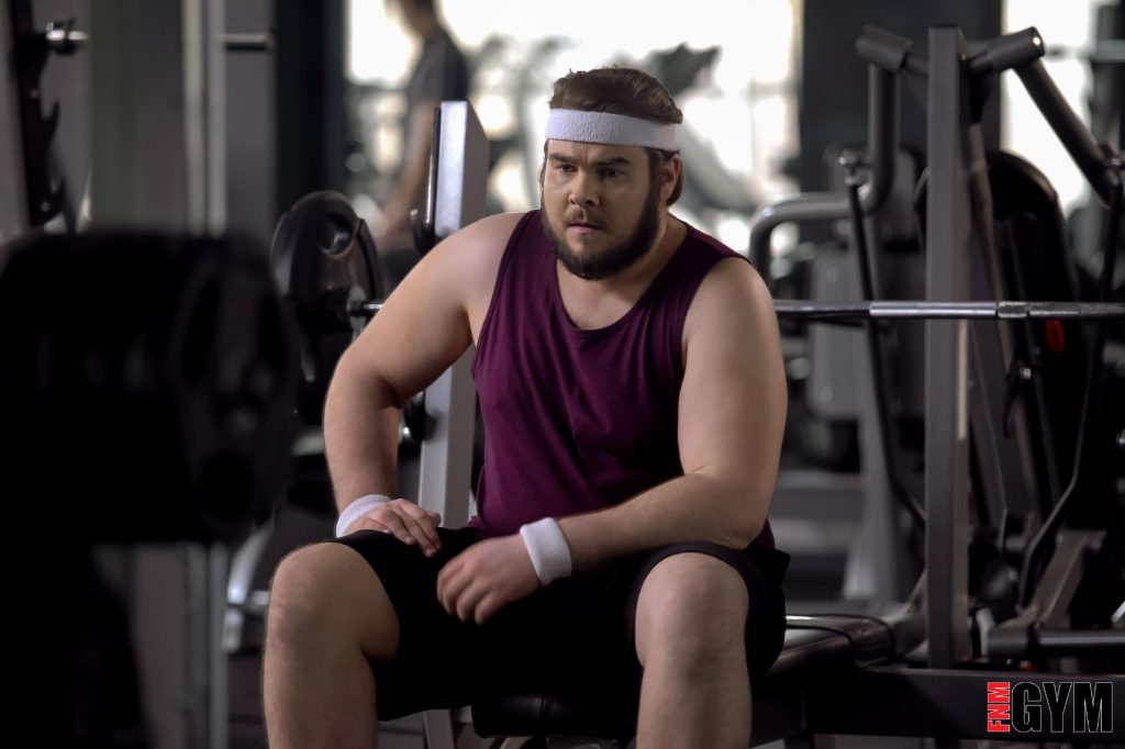 Male wearing purple top and sweat band sitting on bench