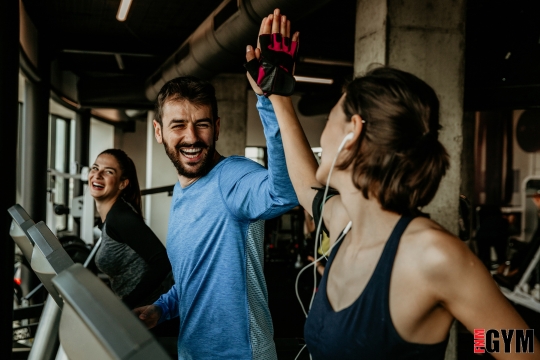 female and male person high fiving in a gym