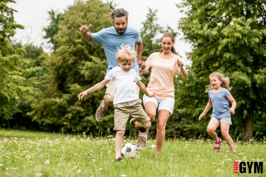 family kicking soccer ball to park