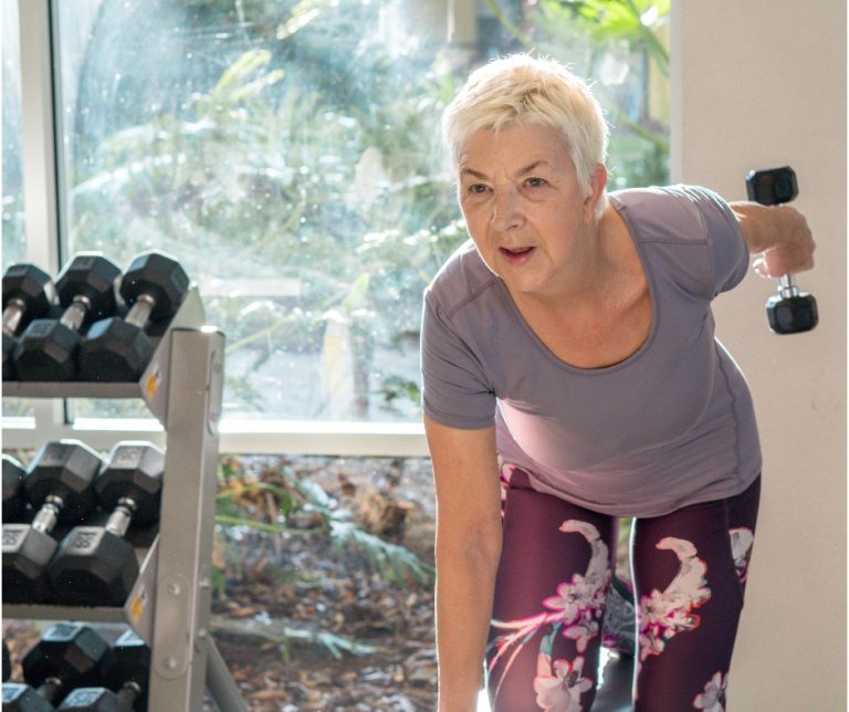 lady using dumbbell leaning on weight training bench