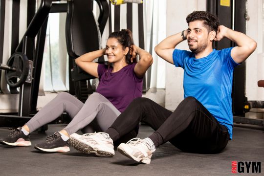 male in blue top and female in purple top doing sit ups