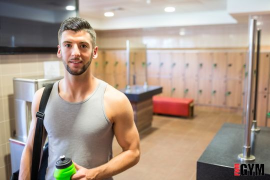 male in grey singlet holding green water bottle in changing rooms