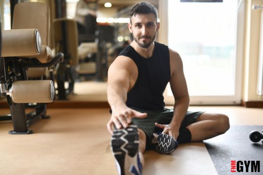 Male wearing black singlet stretching