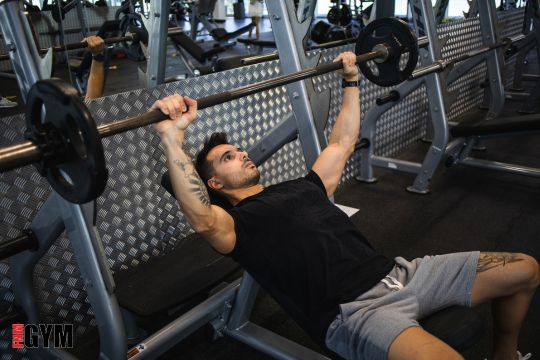 male wearing black tshirt doing bench press