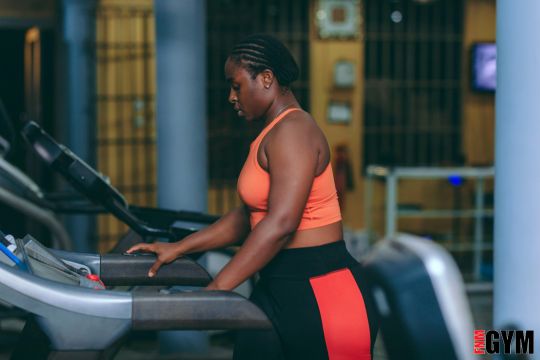 female on treadmill wearing orange crop top